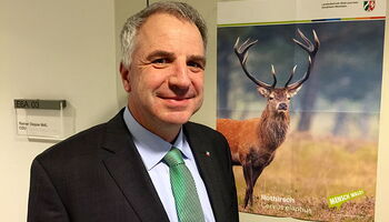 Rainer Deppe MdL vor seiner Bürotür im Landtag mit dem Plakat Rothirsch vom Landesbetrieb Wald und Holz NRW