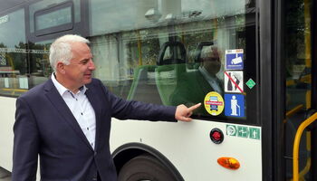 Rainer Deppe zeigt auf einen Aufkleber am Bus, der einen Abbiegeassistenten eingebaut hat